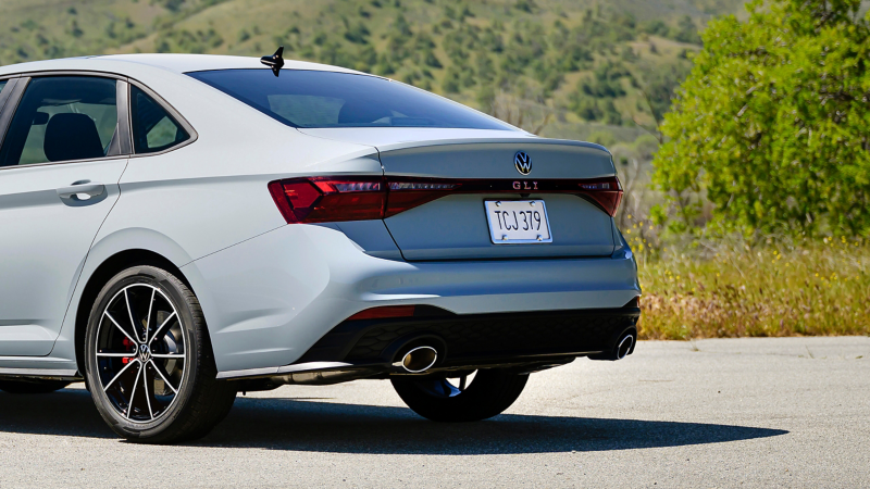 Rear view of a Jetta GLI shown in Monument Gray parked on a mountain road with trees in the background.