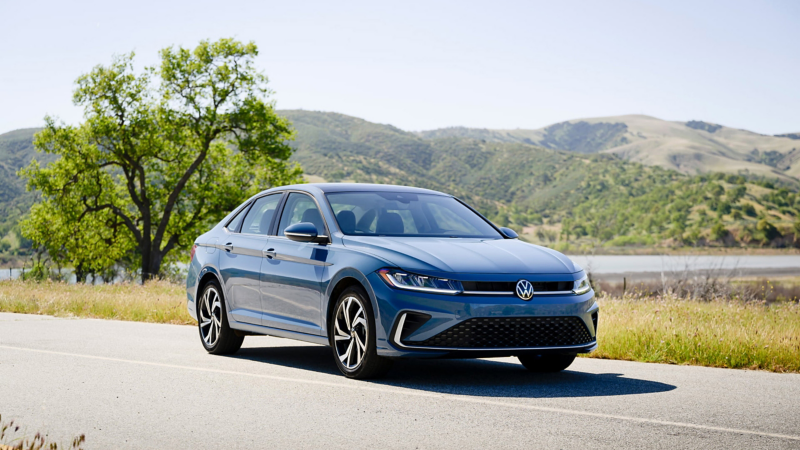 Front view of a Jetta shown in Monterey Blue Pearl parked with wooded hills in the background