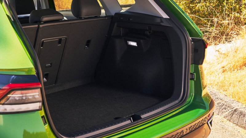 Rear view of a Taos shown in Bright Moss Green parked with the hatch open showing the cargo area.