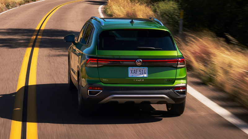 Rear view of a Taos shown in Bright Moss Green driving on a mountain road.