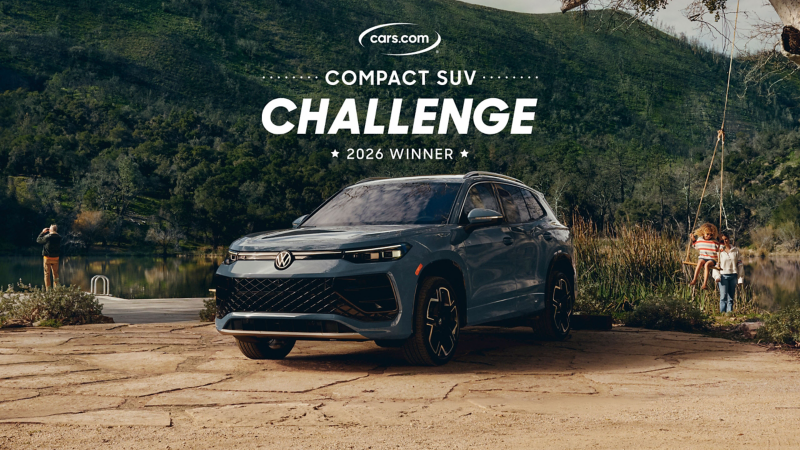 A Tiguan shown in Monterey Blue Pearl is parked by a lake in the woods with the cars.com 2026 Compact SUV Challenge Winner logo floating above the vehicle while a woman pushes a child on a tree swing nearby and a man uses binoculars to birdwatch in the background.