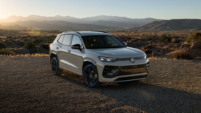 Front view of a Tiguan shown in Sandstone parked with a valley and mountains in the background. 