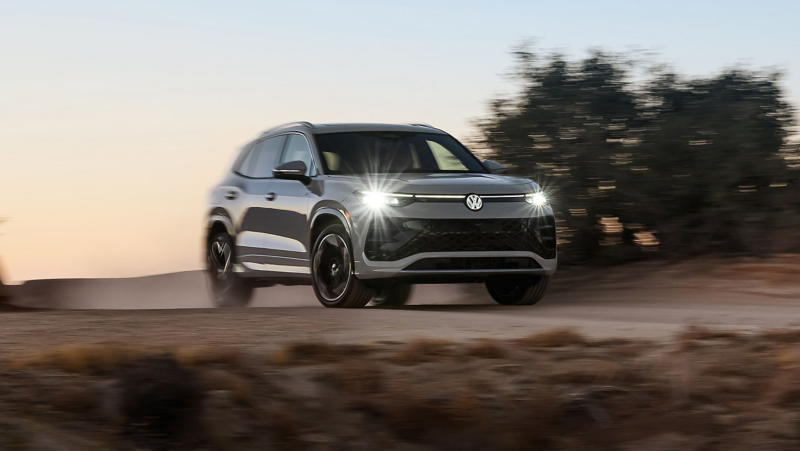 Front view of a Tiguan shown in Sandstone driving on a mountain road at dusk.
