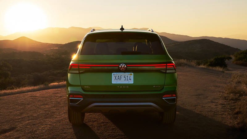 Rear view of a Taos shown in Bright Moss Green parked at dusk with mountains in the background.