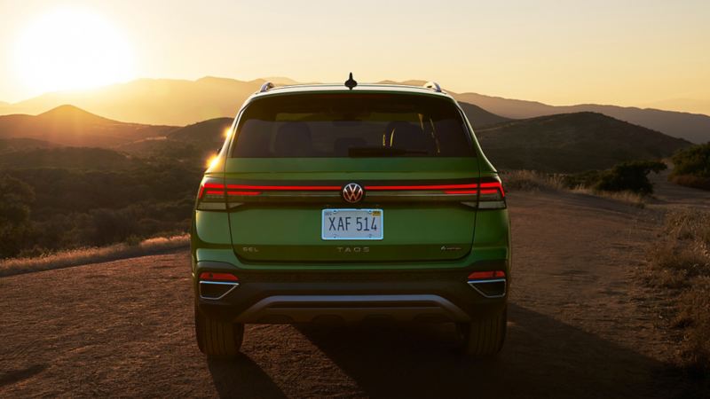 Rear view of a Taos shown in Bright Moss Green parked at dusk with mountains in the background.