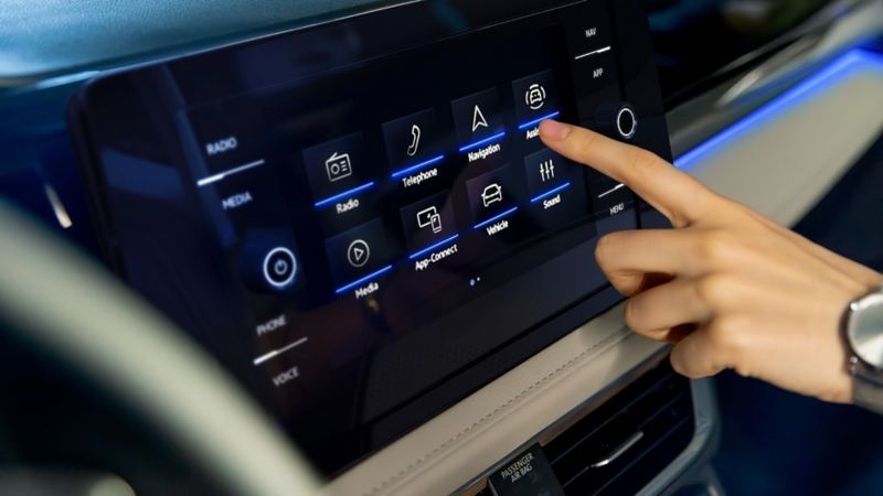 A hand interacts with the touchscreen infotainment display in a Taos.