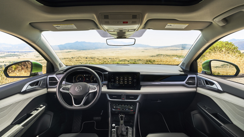 Interior view looking out the windshield of a Taos with a wide plain and mountains visible though the windshield.