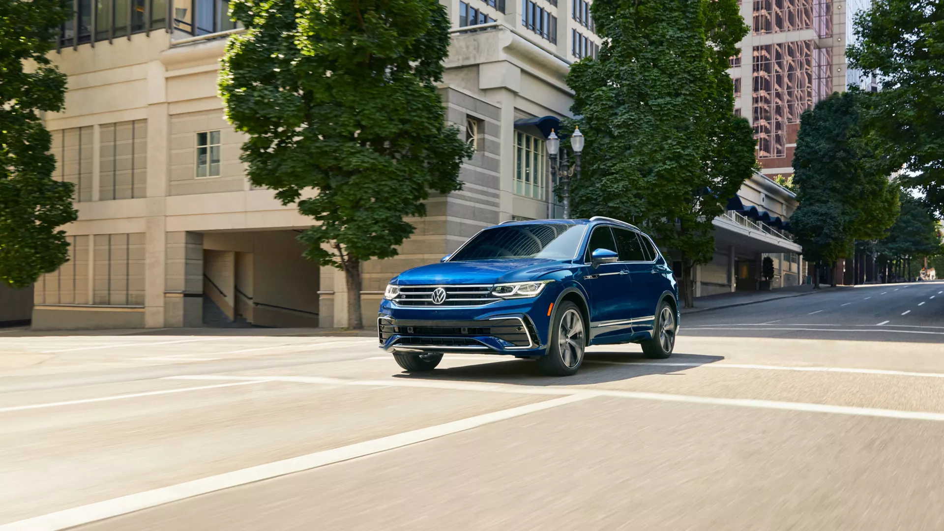 Blue 2024 Volkswagen Tiguan driving on a empty big city street