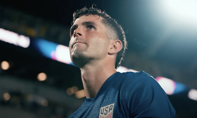 Close up of a soccer player with bright stadium lights in the background.
