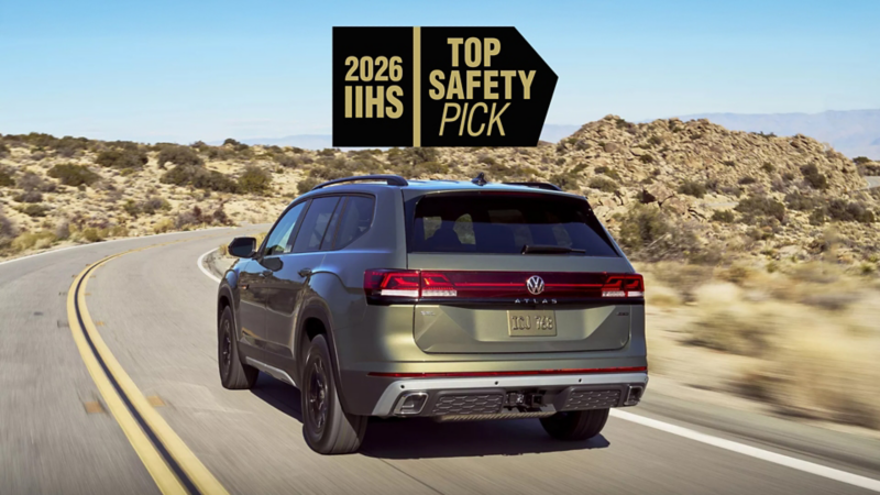 Rear view of an Atlas shown in Avocado Green Metallic driving on a highway through the desert with a safety rating icon overlayed at the top of the image.