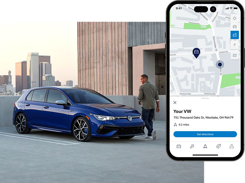 Person walking toward a Golf R shown in Lapiz Blue Metallic parked on a rooftop parking lot. The MyVW app is displayed on a superimposed mobile phone.