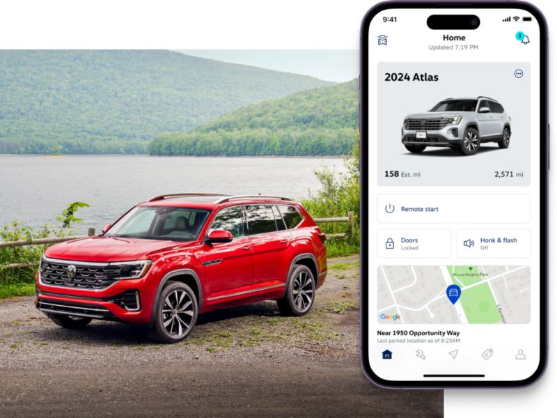 Atlas shown in Aurora Red Metallic parked in front of a lake with a forest in the background. To the right, the MyVW app interface is displayed on a compatible phone.