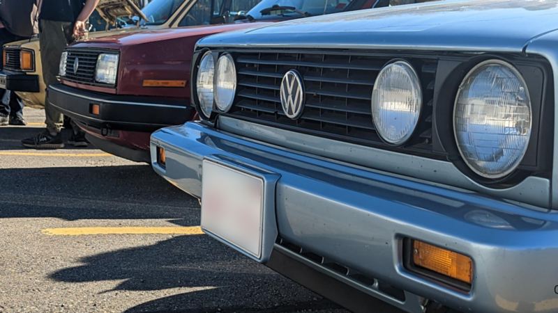Close-up image of the headlights and front grills of two vintage Volkswagens.