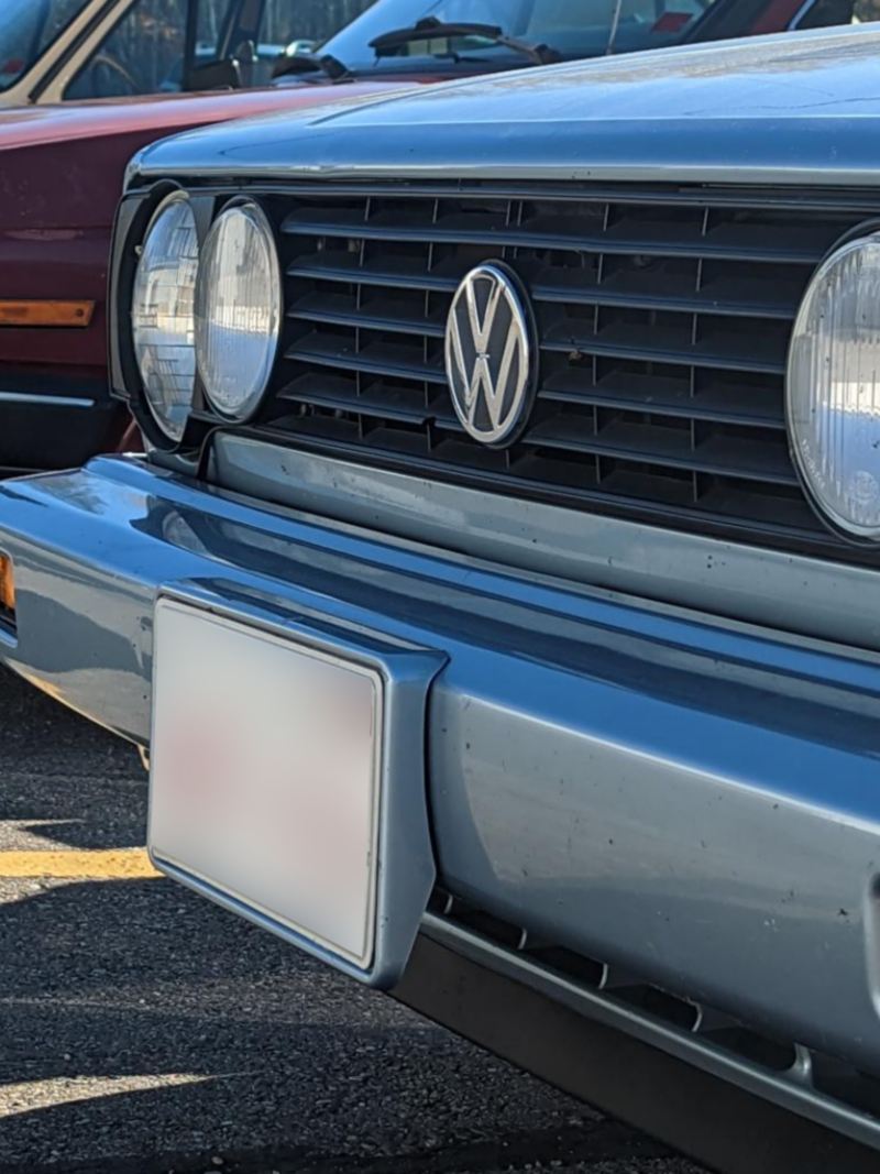 Close-up image of the headlights and front grills of two vintage Volkswagens.