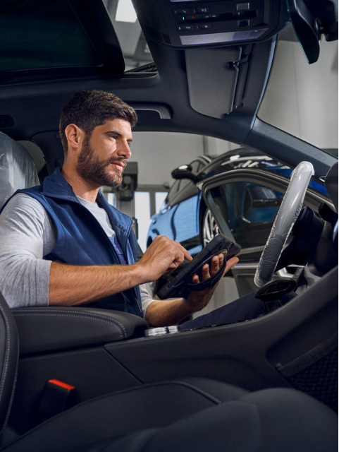 Person in a modern car, using a device in the driver's seat.