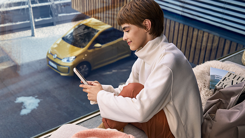 Persona relajándose en el interior con vista a un Volkswagen amarillo.