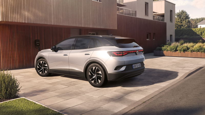 Silberner VW ID.4 ENERGY vor modernem Haus mit Holzfassade.