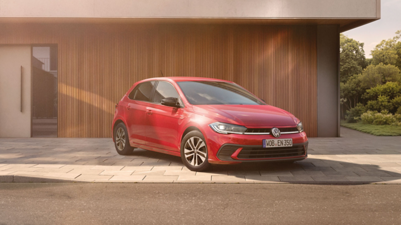 Ein VW Polo steht vor einem Haus mit Holzfassade.