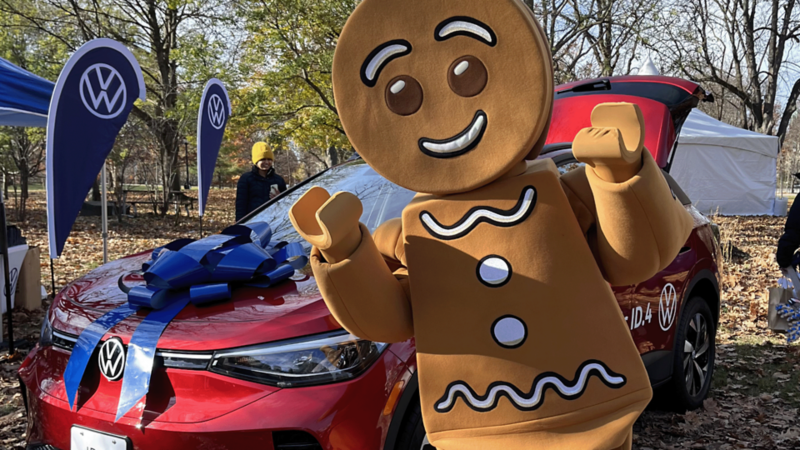 Une personne déguisée en bonhomme de pain d’épices est debout devant un ID.4 de VW.