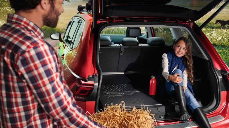Una bambina seduta nel bagagliaio di una vettura Volkswagen rossa