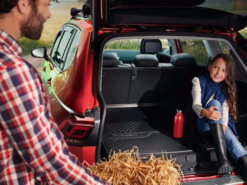 Una bambina seduta nel bagagliaio di una vettura Volkswagen rossa