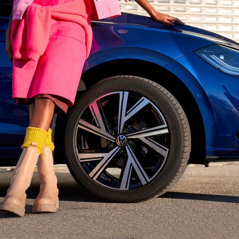 Donna appoggiata al fianco della sua Volkswagen blu 