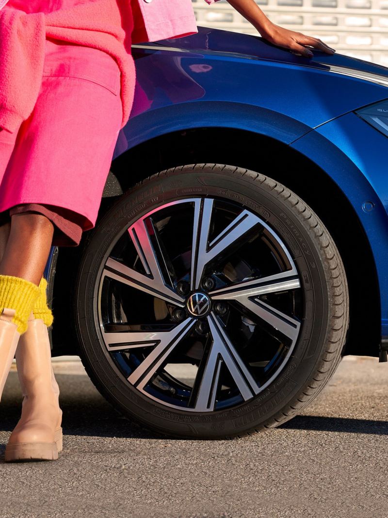 Donna appoggiata al fianco della sua Volkswagen blu 