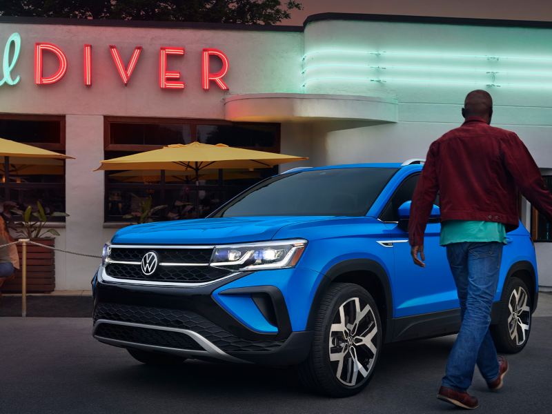 We see a man walking toward a bright blue Taos.