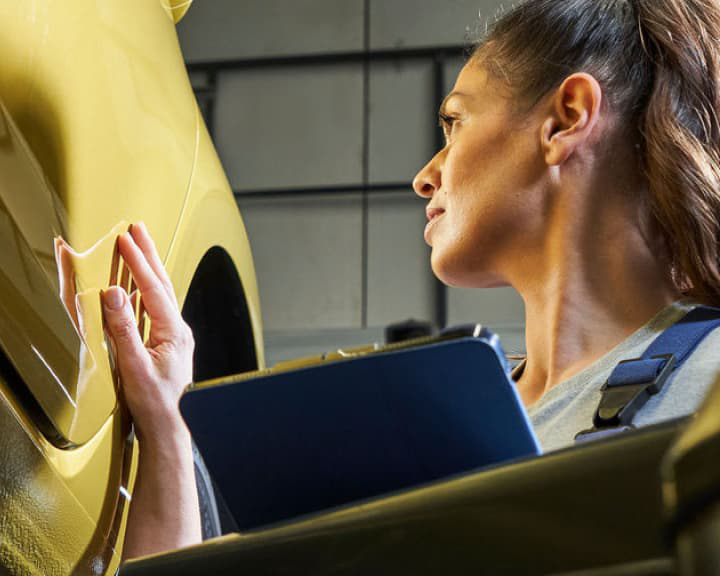 Una persona inspecciona un auto amarillo para garantizar la calidad a los posibles propietarios.