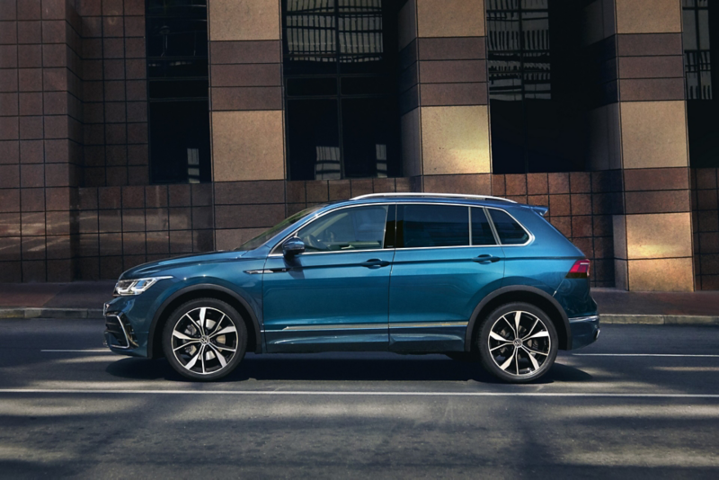 en blå Volkswagen Tiguan står parkerad utanför en byggnad
