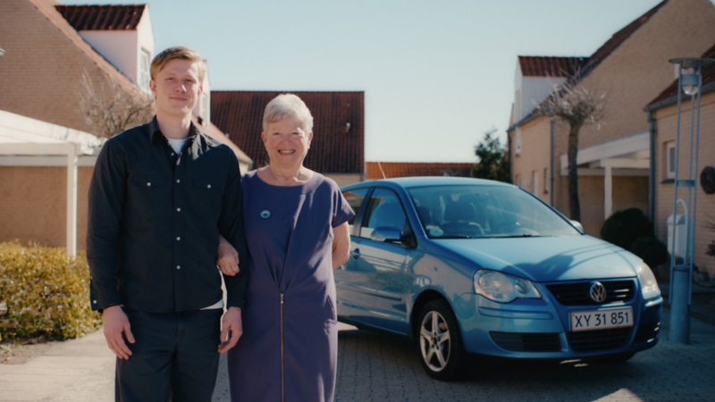 En ung mand og hans mormor står foran en gammel polo