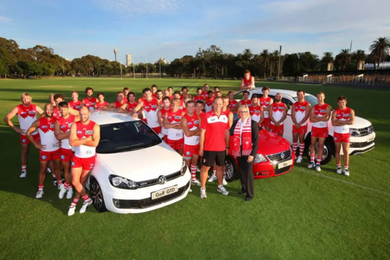 Sydney Swans team stood on field with three VW cars 