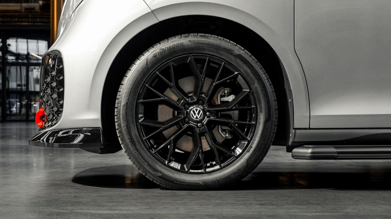 Zwarte meerspaaks lichtmetalen velg onder een witte Volkswagen met een glanzend zwarte frontsplitter.