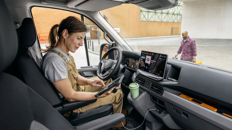 Bestuurder in een Volkswagen Crafter gebruikt een tablet bij het dashboard met groot infotainmentscherm.
