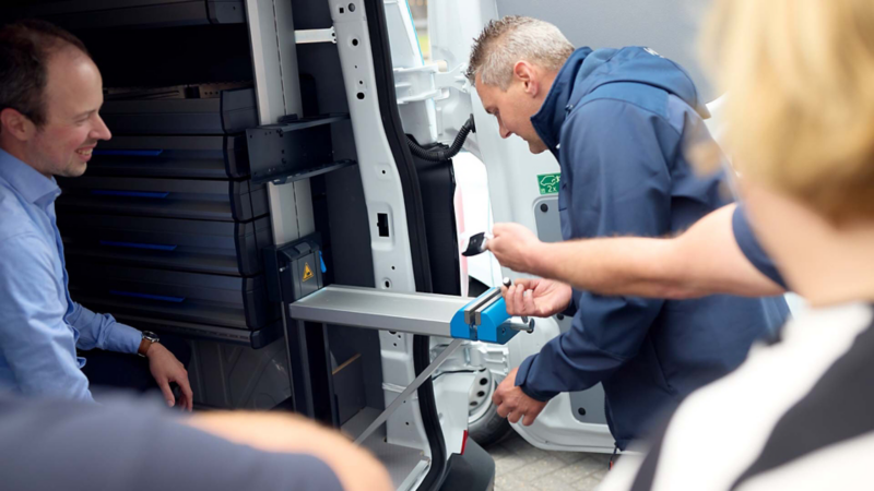Een van de nieuwe berijders van de Volkswagen e-Transporters van Maasdelta Groep inspecteert de bedrijfswageninrichting van zijn nieuwe bus