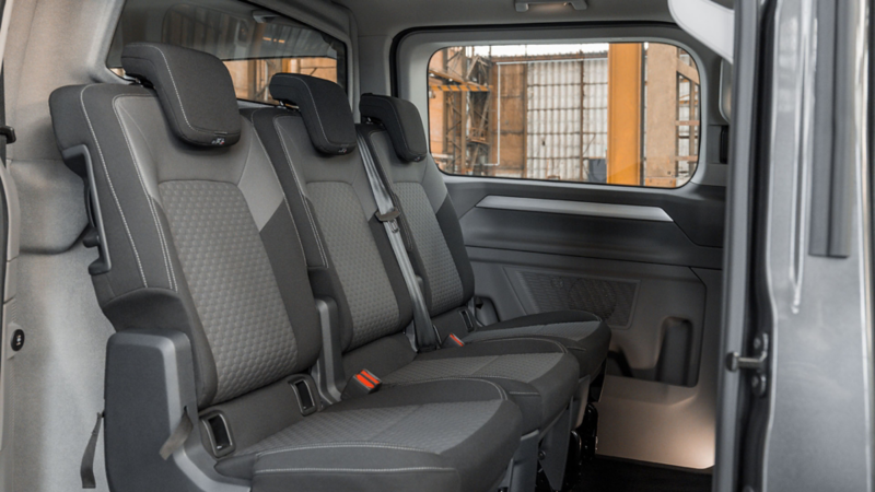 Drie grijze stoffen zitplaatsen op de tweede zitrij van een Volkswagen Caravelle eHybrid. toCargo