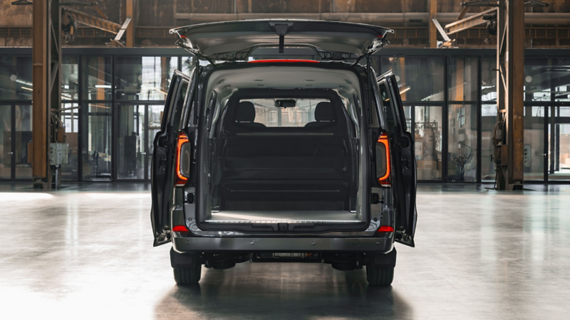 Achteraanzicht van een grijze Volkswagen Caravelle eHybrid to Cargo met geopende achterklep en schuifdeuren die de lege laadruimte tonen.