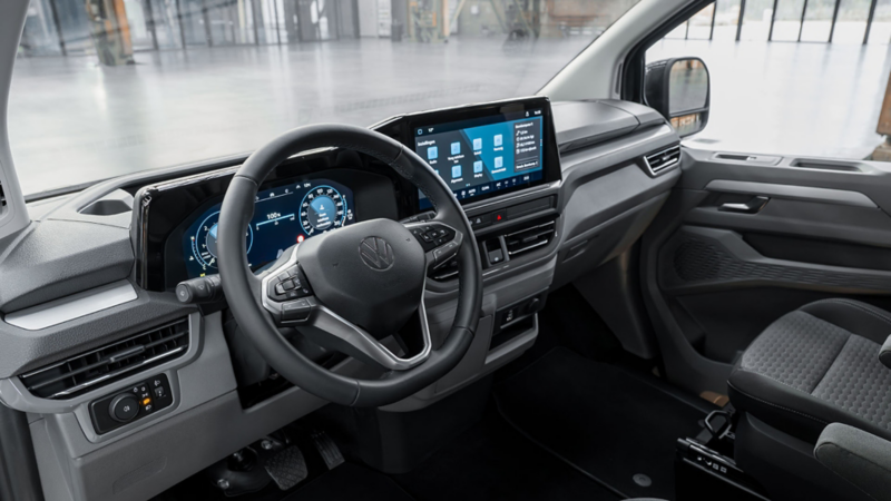 Dashboard van een Volkswagen Caravelle eHybrid toCargo met digitale cockpit, groot centraal touchscreen en lederen multifunctioneel stuurwiel.