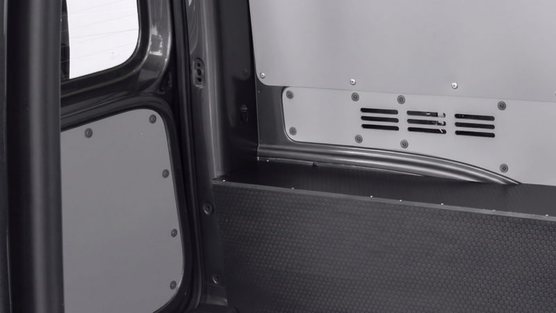 Zwarte vierkante wielkastbescherming met antislipstructuur en grijze zijwandbekleding in een laadruimte.