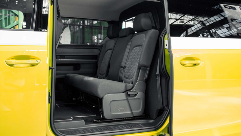 Interieur van een geel-witte Volkswagen ID. Buzz toCargo met een driezits achterbank en een scheidingswand.
