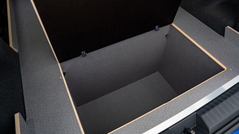 Geopend luik in de vlakke laadvloer dat een diepe, verborgen opbergruimte eronder onthult.