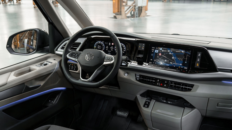 Dashboard van een Volkswagen Multivan eHybrid toCargo met digitale cockpit, navigatie op het centrale scherm en blauwe sfeerverlichting.