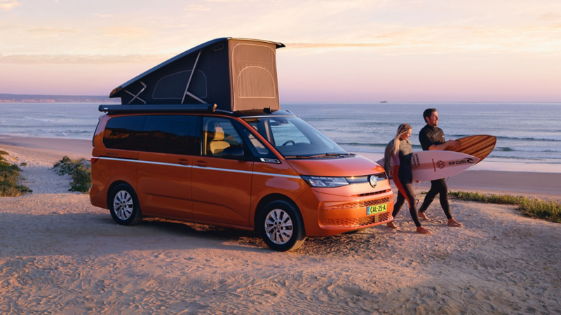 Nieuwe Volkswagen California met twee surfers met surfplanken