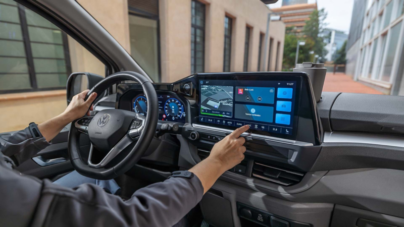 Het interieur van de nieuwe Transporter met iemand die het centrale touchscreen bedient