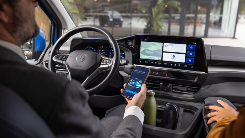 Man die smartphone in zijn hand heeft en gebruik maakt van de VW Connect diensten