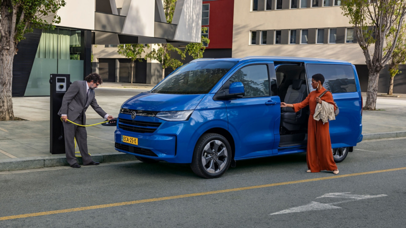 De nieuwe Volkswagen e-Caravelle met persoon bij laadpaal en persoon die aan het instappen is