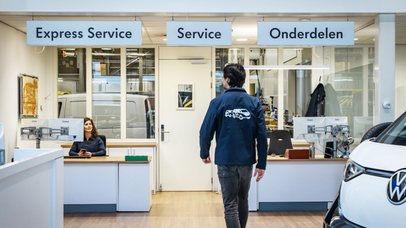 Een klant die richting de servicebalie loopt in de showroom van Volkswagen Bedrijfswagens