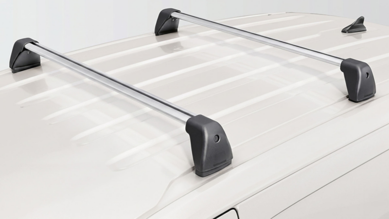 Twee zilverkleurige allesdragers met zwarte eindkappen gemonteerd op het dak van een witte Volkswagen bedrijfswagen.
