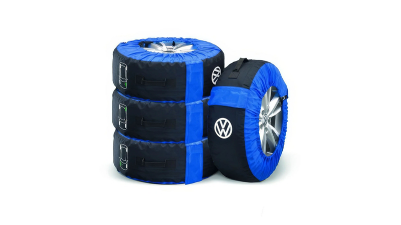 Vier zwarte en blauwe Volkswagen bandenhoezen met handgrepen en icoontjes voor de wielpositie.