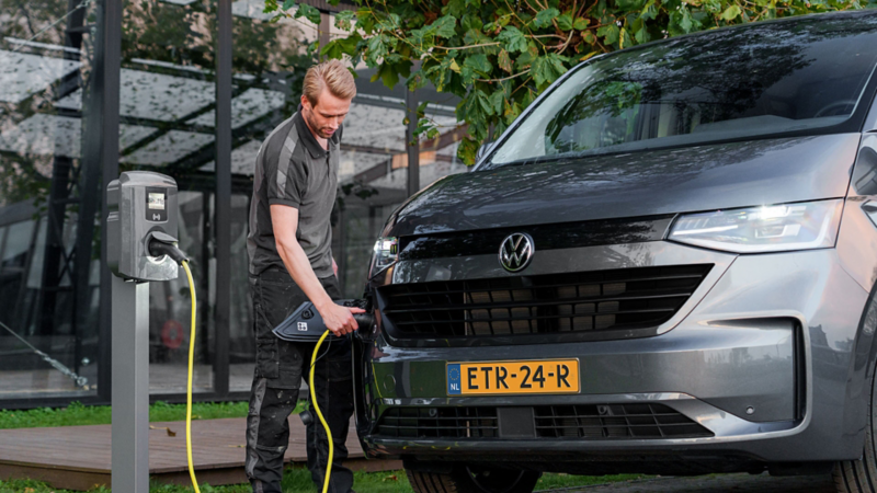 Persoon naast de nieuwe e-Transporter die de laadkabel aan het aansluiten is